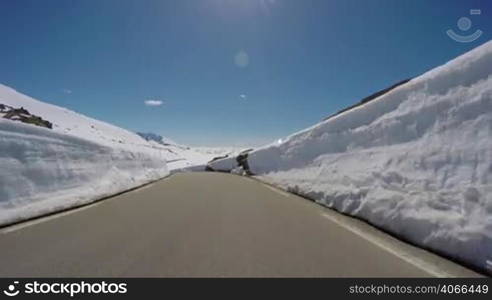 Driving a Car on a Mountain road in Norway with high snow wall