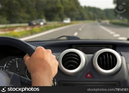Driving a car with a hand on the steering wheel