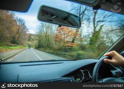 Driving car. Hands of driver on steering wheel of a car and asphalt road.