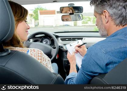 Driving instructor and learner in front of car