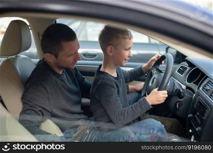 Driving instructor, driving school, child driving, dad and son, long trip, hold the steering wheel, car device, family day. Dad shows his little son how to drive a car