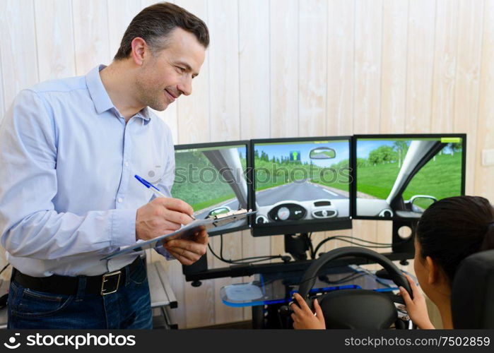 driving instructor watching learner driver use driving simulator