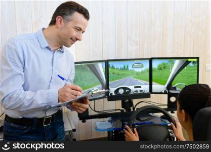 driving instructor watching learner driver use driving simulator