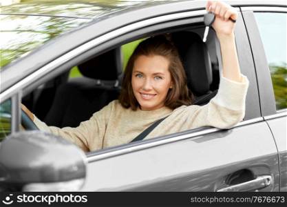 driving, safety and people concept - young woman or female driver sitting in car and showing key. woman or female driver with car key in city