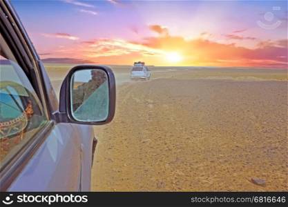 Driving through the Sahara Desert in Morocco at sunset