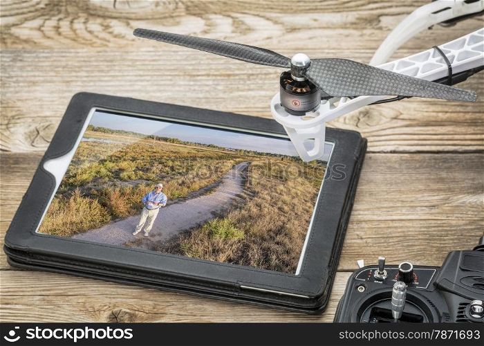 drone aerial photography concept - reviewing aerial picture (drone operator in a field) on a digital tablet with a drone rotor and radio control transmitter,