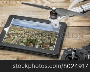 drone aerial photography concept - reviewing aerial picture of residential area on a digital tablet with a drone rotor and radio control transmitter,