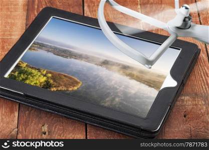 drone aerial photography concept - reviewing aerial pictures of a foggy lake on a digital tablet with a drone rotor, screen picture created by the photographer