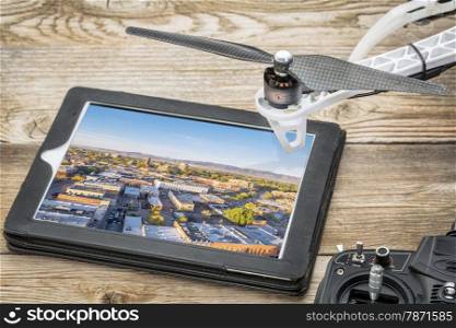 drone aerial photography concept - reviewing aerial pictures of Fort Collins downtown on a digital tablet with a drone rotor and radio control transmitter,