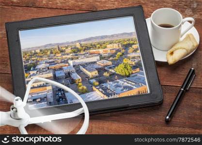 drone aerial photography concept - reviewing aerial pictures of Fort Collins downtown on a digital tablet with a drone rotor and cup of coffee