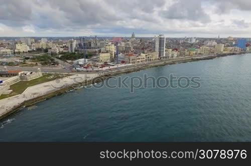 Drone flying over Havana, Cuba: Caribbean sea and Malecon promenade. Aerial view of La Habana skyline, Cuban capital city. Urban landscape seen from the sky with old buildings and ocean.
