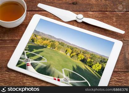 drone flying over park in fall colors - reviewing aerial image on a digital tablet with a cup of tea