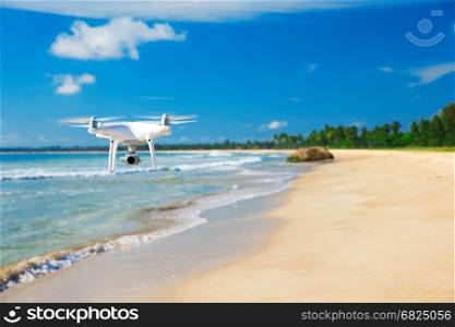 drone flying over sea. white drone hovering in a bright blue sky. New technology in the aero photo shooting.
