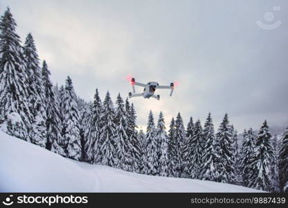 Drone just got up in flight after snowfall near trees