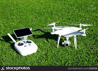 drone quad copter with high resolution digital camera and its remote control pad with smartphone on grass