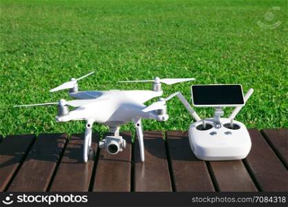 drone quad copter with high resolution digital camera and its remote control pad with smartphone on grass