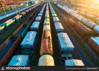 Drone view of freight trains at sunset. Colorful railway cargo wagons with goods on railroad. Aerial view of colorful wagons. Depot of freight trains. Railway station. Heavy industry. Transportation. Drone view of freight trains at sunset. Railway cargo wagons