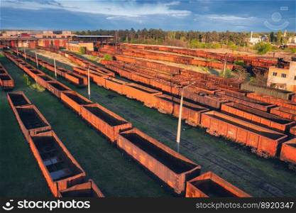 Drone view of freight trains at sunset. Old Railway cargo wagons with on railroad. Aerial view of colorful wagons. Depot of freight trains. Railway station. Heavy industry. Industrial. Transportation