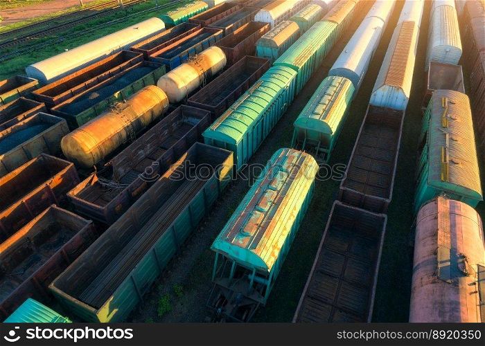 Drone view of freight trains at sunset. Railway cargo wagons with goods on railroad. Aerial view of colorful wagons. Depo of freight trains. Railway station. Heavy industry. Industrial. Transportation