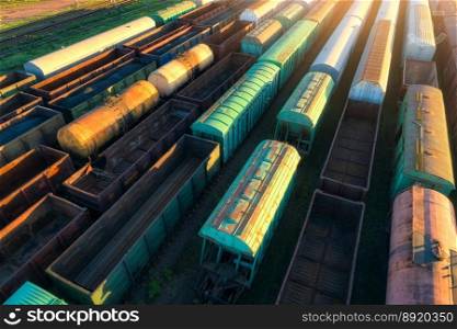 Drone view of freight trains at sunset. Railway cargo wagons with goods on railroad. Aerial view of colorful wagons. Depo of freight trains. Railway station. Heavy industry. Industrial. Transportation