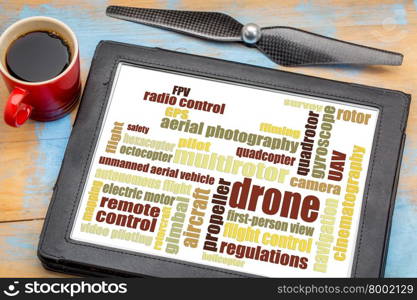 drone word cloud on a digital tablet with a cup of coffee and a drone propeller against a grunge painted wood