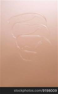 Drop of cosmetic transparent gel on a beige background. The texture of the serum, heir gel or hyaluronic booster.