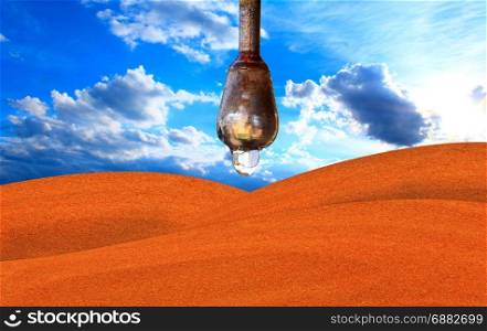 drop of water hanging above the desert. drop of water hanging above the desert and blue sky