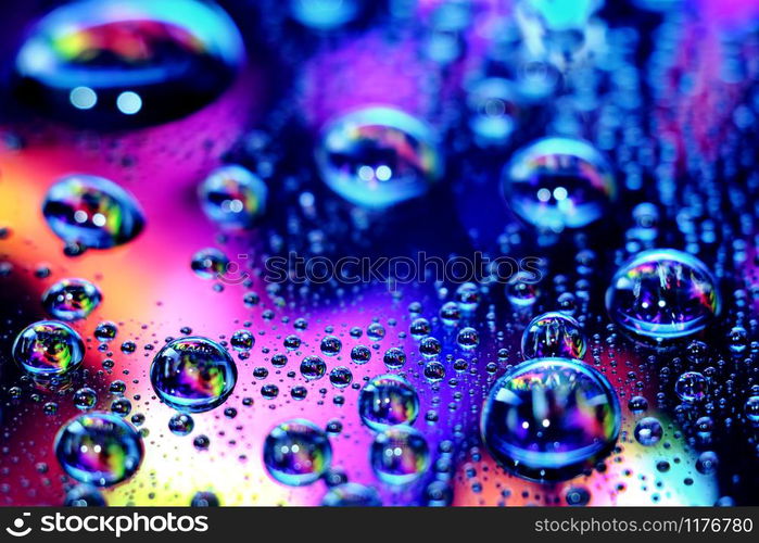 Droplets of water in a vivid colorful blurry background. Droplets in abstract colors.