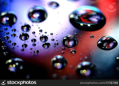 Droplets of water in a vivid colorful blurry background. Droplets in abstract colors.