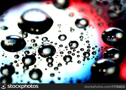 Droplets of water in a vivid colorful blurry background. Droplets in abstract colors.