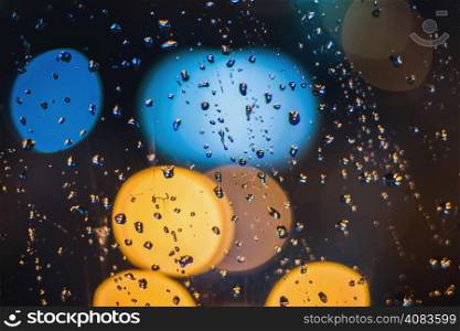 Drops of night rain on window and lights of the street