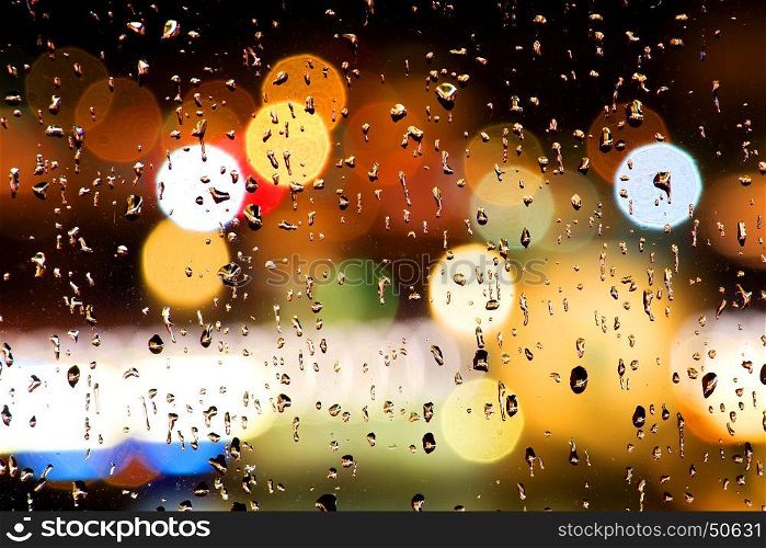 Drops of rain on window with abstract bokeh lights