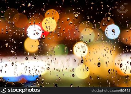 Drops of rain on window with abstract bokeh lights