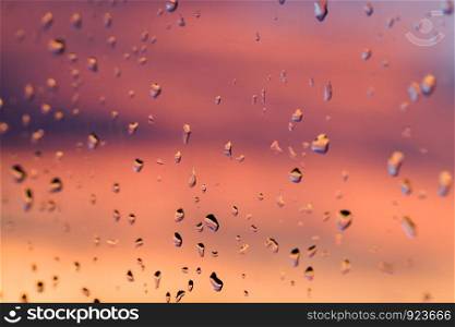 drops of water after the rain on the glass, through which colors colorful beautiful sunset, bright colors in the background. drops of water