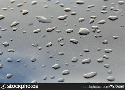 drops on a gray mirror surface which reflects the sky