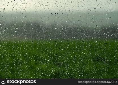 Drops on window with landscape and natural color background. Concept for rain and bad weather.