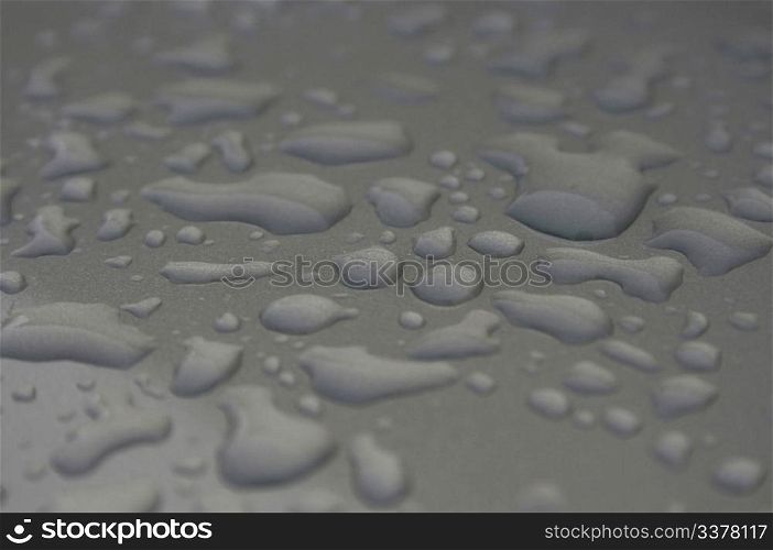 Drops water after rain on the silvery metal surface. Shallow depth of field. Focus on the center of frame
