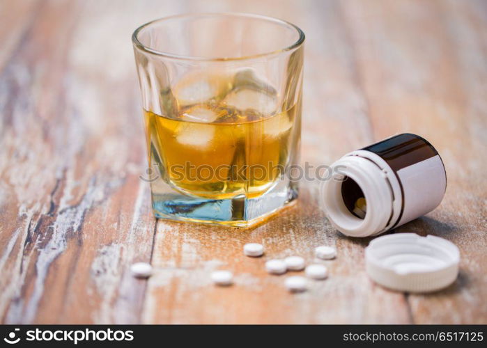 drug abuse, addiction and suicide concept - glass of alcohol and pills on table. glass of alcohol and pills on table. glass of alcohol and pills on table
