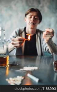 Drug addict with a spoon and matches prepares a dose. Narcotic addiction concept, addicted people, junkie. Drug addict with spoon and matches prepares a dose