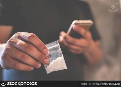 Drug dealer selling junkie. Man hand holds plastic packet or bag with addict narcotics cocaine powder or another, drug dealer sale and danger addiction overdose concept.