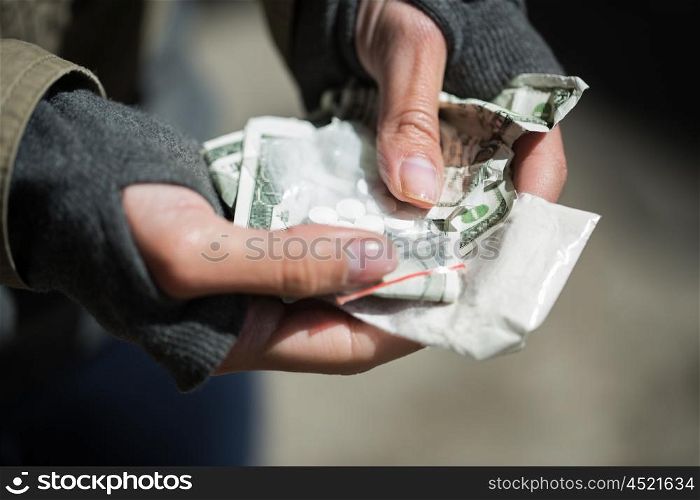 drug trafficking, crime, addiction and sale concept - close up of addict hands with drugs and money