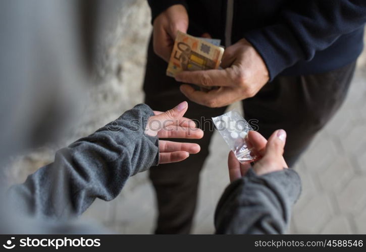 drug trafficking, crime, addiction and sale concept - close up of addict with money buying dose from dealer on street