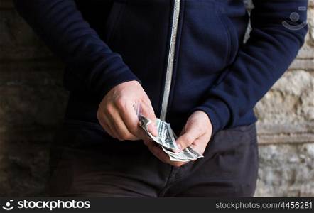 drug trafficking, crime, addiction, people and sale concept - close up of addict or dealer hands with dollar money and dose