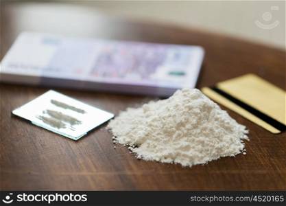 drug use, crime, addiction and substance abuse concept - close up of crack cocaine drug dose track on mirror with credit card and money