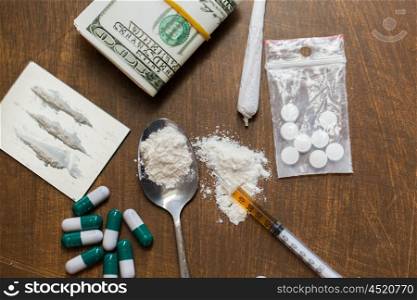 drug use, crime, addiction and substance abuse concept - close up of drugs with money, spoon and syringe