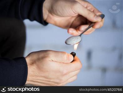 drug use, crime, addiction, substance abuse and people concept - close up of addict with lighter and spoon preparing dose of crack cocaine on street
