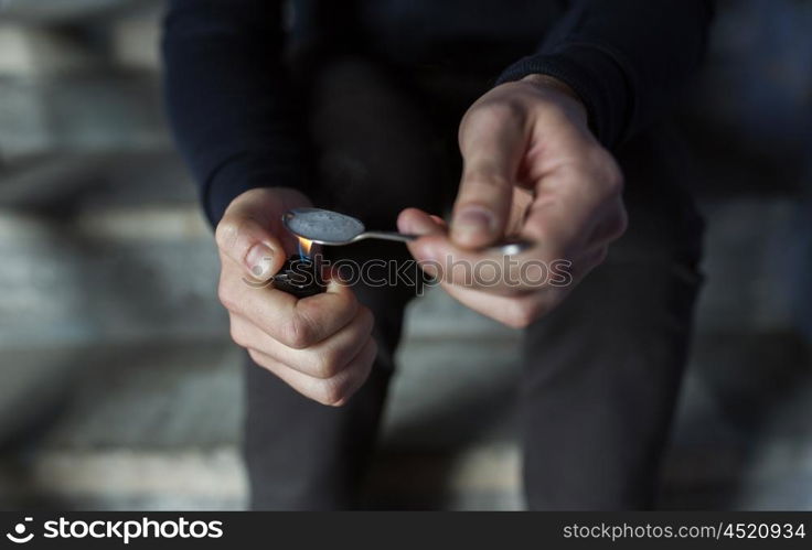 drug use, crime, addiction, substance abuse and people concept - close up of addict with lighter and spoon preparing dose of crack cocaine on street