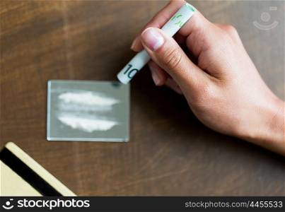 drug use, people, addiction and substance abuse concept - close up of addict hand with crack cocaine drug dose track on mirror, credit card and money roll
