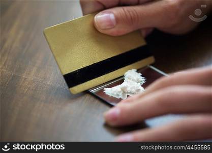 drug use, people, addiction and substance abuse concept - close up of addict hands with crack cocaine drug dose track on mirror and credit card