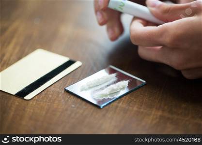 drug use, people, addiction and substance abuse concept - close up of addict hands with crack cocaine drug dose track on mirror, credit card and money roll